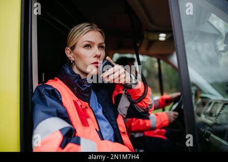 Porträt einer jungen Ärztin, die im Krankenwagen in ein Walkie-Talkie sitzt und spricht. Stockfoto