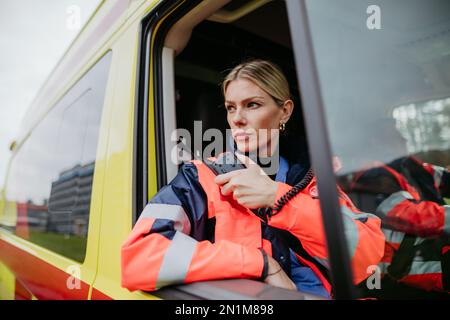 Porträt einer jungen Ärztin, die im Krankenwagen in ein Walkie-Talkie sitzt und spricht. Stockfoto