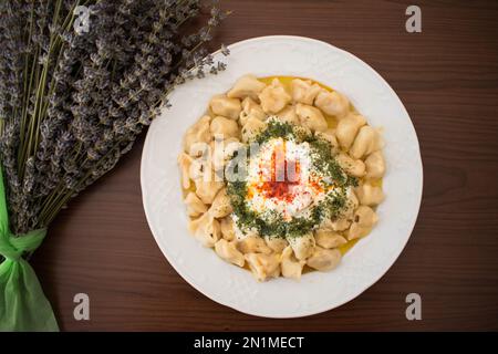 Traditionelle türkische Ravioli mit Joghurt, Butter und Gewürzen, Draufsicht. Stockfoto