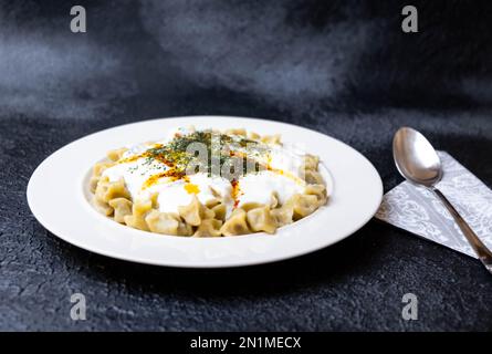 Traditionelle türkische Ravioli mit Joghurt, Butter und Gewürzen, Nahaufnahme. Stockfoto