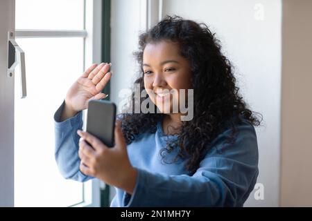 Schöne, dicke junge Frau, die zu Hause Selfies mit dem Telefon macht Stockfoto
