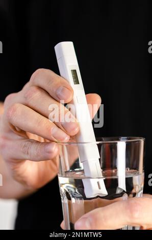 Wasserqualitätsprüfer in einem Glas Wasser. Messung der Trinkwasserqualität. Stockfoto