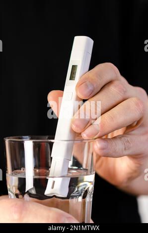 Wasserqualitätsprüfer in einem Glas Wasser. Messung der Trinkwasserqualität. Stockfoto