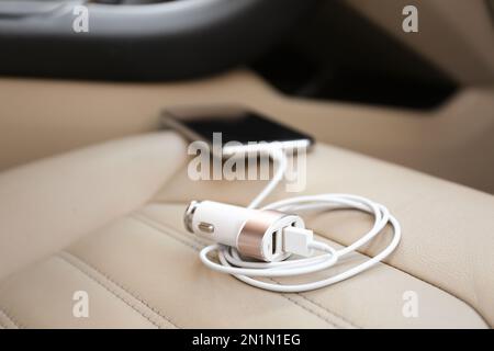 Adapter mit angeschlossenem Ladekabel und Mobiltelefon im Auto, Nahaufnahme Stockfoto