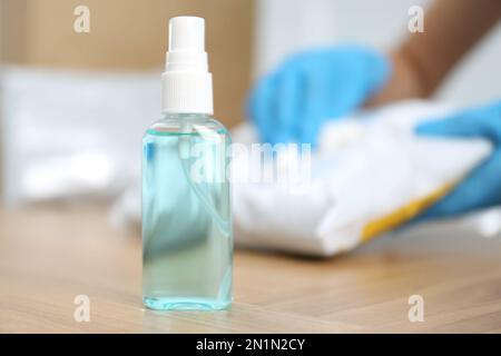 Antibakterielles Spray und verschwommene Person mit Paket auf Hintergrund, Platz für Text. Präventivmaßnahme während der COVID-19-Pandemie Stockfoto
