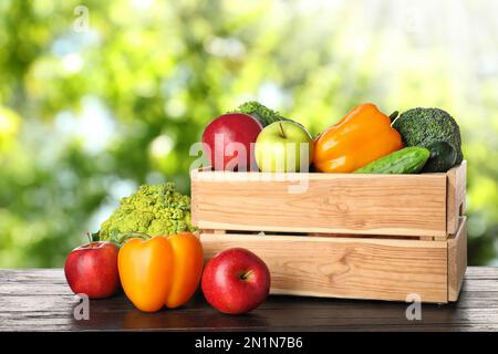 Holzkiste mit frischem Gemüse und Obst auf dem Tisch vor verschwommenem Hintergrund Stockfoto