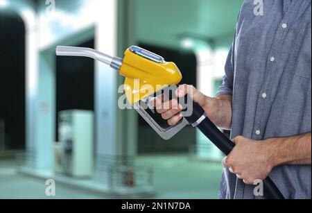 Ein Mann, der die Tankdüse in der Nähe der Tankstelle hält, Nahaufnahme Stockfoto