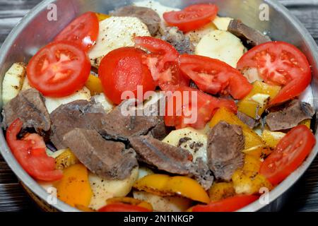 Ein Tablett mit Kartoffelscheiben, Zwiebeln, Tomaten, farbigem Pfeffer, Fleischstücken, Gewürze, Knoblauch und Paprika, selektiver Schwerpunkt von Kartoffeln mit Rindfleisch und Gemüse Stockfoto