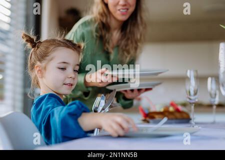 Nahaufnahme der Mutter mit ihrer Tochter, die den Tisch gedeckt hat, um Ostern zu feiern. Stockfoto