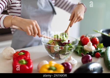 Chefköchin bereitet frischen Gemüsesalat zu, bereitet zu Hause das Essen zu Stockfoto