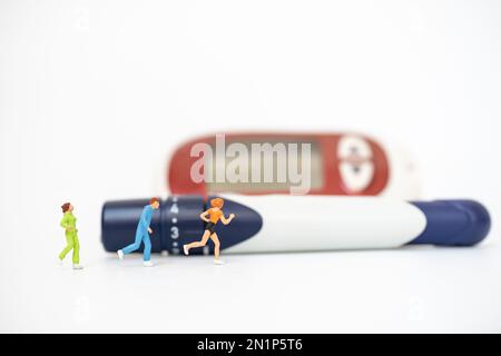 Läufer-Miniaturfigur Leute laufen mit Lanzette und Glukose-Messgerät auf weißem Hintergrund. Verwendung als Sportmedizin, Diabetes, Glykämie, Gesundheitswesen und p Stockfoto