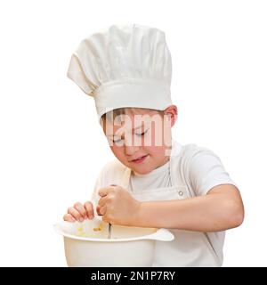 Ein Junge in weißer Koch-Kleidung kocht in einer Küche zu Hause, isoliert auf weißem Hintergrund Stockfoto