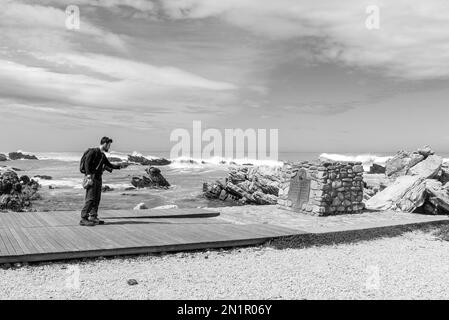 Agulhas-Nationalpark, Südafrika - 22. September 2022: Touristen fotografieren mit dem Handy die Plakette am Kap L'Agulhas, der südlichsten Spitze von AFR Stockfoto