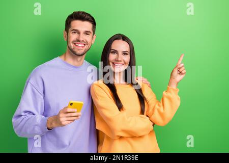 Foto eines Ehemanns, dessen Frau Sweatshirts gekleidet hat, die leeren Raum zeigen, twitter-Telegramm mit facebook-isoliertem grünen Hintergrund chatten Stockfoto