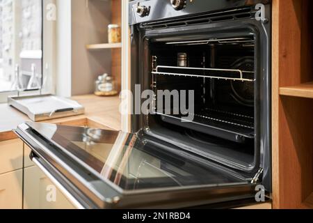 Elektrischer Ofen mit Belüftung. Seitenansicht eines modernen Technikgerätes gegen Küchenmöbel. Stockfoto