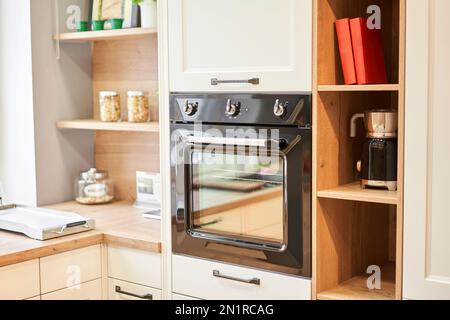 Elektrischer Ofen mit Belüftung. Seitenansicht eines modernen Technikgerätes gegen Küchenmöbel. Stockfoto