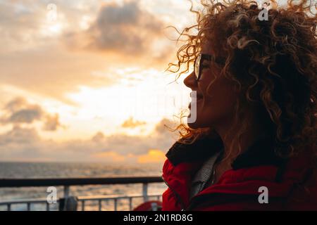 Reise und Glück Expression Seitenporträt Konzept. Eine Frau lächelt und genießt die Freiheit. Junge Touristenfrau mit Sonnenuntergang und Ozean in Ba Stockfoto