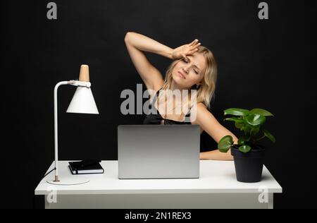 Frustrierte, unzufriedene Notebook-Benutzerin, die den Kopf am Arbeitstisch mit dem Computer berührt, Stress, Ermüdung, Burn-out durchmacht, schlechte Nachrichten bekommt. Trauriger Angestellter Stockfoto
