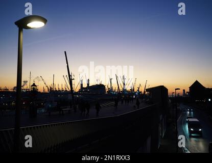 Hamburg, Deutschland. 06. Februar 2023. Passanten gehen entlang der Jan Fedder Promenade im Hafen in der Abendsonne. Kredit: Marcus Brandt/dpa/Alamy Live News Stockfoto