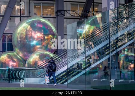 Büroangestellte fahren Rolltreppen neben einem Kunstwerk mit dem Titel „Evanescent“, das im Januar und Februar im Leadenhall Building in der City of London, dem Finanzviertel der Hauptstadt, am 6. Februar 2023 in London, England, ausgestellt wird. Evanescent ist ein kostenloser Besuch einer öffentlichen Anlage mit einer Ansammlung gigantischer Blasen, die zusammen auf mehr als sieben Meter Höhe steigen. Das Werk von Atelier Sisu wurde neben dem Westeingang des Leadenhall-Gebäudes, auch bekannt als „Cheesegrater“, platziert. Stockfoto