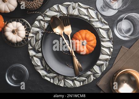 Herbsttisch mit goldenem Besteck und Kürbissen auf schwarzem Hintergrund, flach liegend Stockfoto