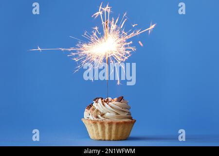 Cupcake mit brennendem Funkel auf hellblauem Hintergrund Stockfoto