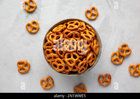 Mini-Brezeln mit Salz in einer Schüssel auf grauem Hintergrund, Draufsicht. Flach liegend, über Kopf, von oben. Stockfoto