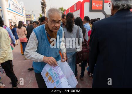 Kolkata, Westbengalen, Indien - 2. Februar 2020 : der alte Buchliebhaber sucht bei Bookfair nach Lieblingsbüchern mit einer Karte zur Buchmesse in der Hand. Stockfoto