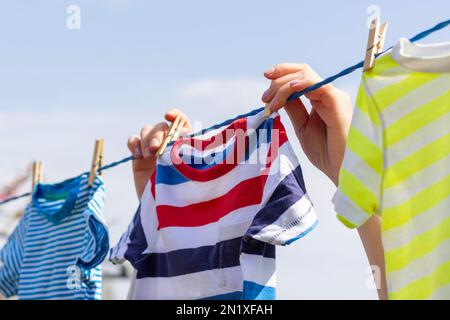 Saubere Kleidung am Seil im Freien am Wäschetag Stockfoto