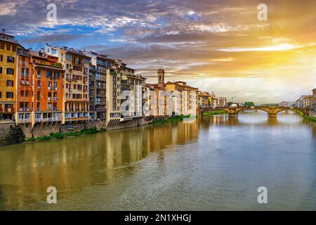 Malerische Sonnenuntergangslandschaft über dem Fluss Arno, die St. Trinity Bridge und farbenfrohe alte Häuser am Fluss in Florenz, Toskana, Italien Stockfoto