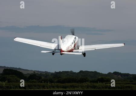 Ein Piper PA-28-151 Cherokee verlässt einen privaten Flugplatz in East Sussex UK in den Abendhimmel Stockfoto