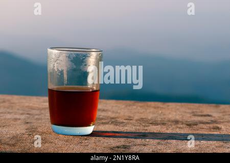 Schwarzer Tee in transparentem Glasbecher isoliert mit blauem Himmel Stockfoto