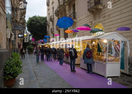 CATANIA, SIZILIEN - 22. APRIL 2019: Besucher besuchen einen offenen Markt in einer Straße von Catania, Sizilien Stockfoto