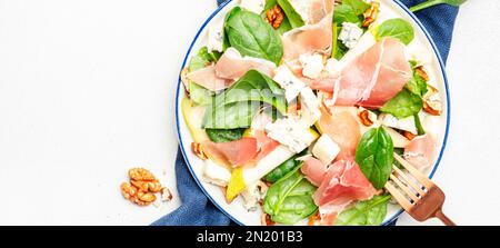 Köstlicher Birnensalat mit Jamon, Blauschimmelkäse, Spinat und Walnüssen auf weißem Tischhintergrund, Banner mit Draufsicht Stockfoto