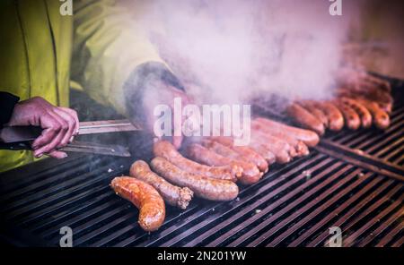 Nahaufnahme der Hände eines Mannes, der hausgemachte Würstchen grillt Stockfoto