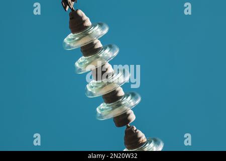 Hochspannungsglas Isolatoren elektrische Leitungen Nahaufnahme mit blauem Hintergrund Stockfoto