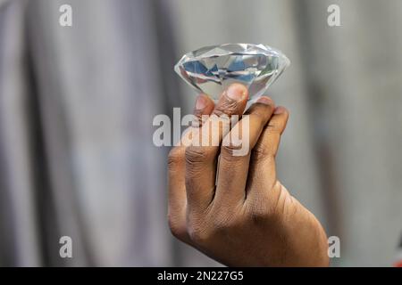 Konzentrieren Sie sich auf den Vordergrund von Fingern, die einen Diamanten halten. Stockfoto