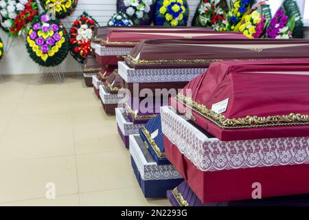 Innenraum des Raumes mit Bestattungszubehör. Geschäft mit Särgen, Beerdigungskränzen und Blumen. Stockfoto