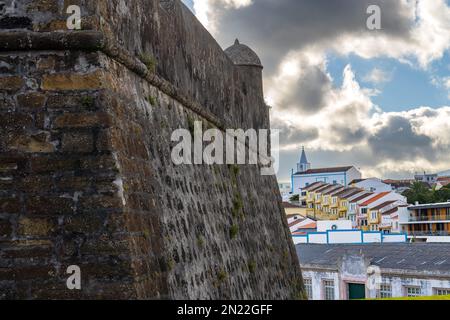 Die riesigen Steinmauern der Küste Forte de São Sebastião aus dem 16. Jahrhundert und Blick auf das Hafengebiet in Angra do Heroismo, Terceira, Azoren, Portugal. Stockfoto