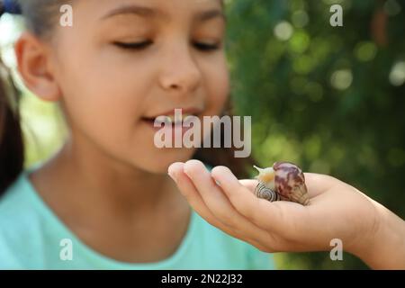 Kinder, die draußen mit süßen Schnecken spielen, konzentrieren sich auf die Hand. Kinder verbringen Zeit in der Natur Stockfoto