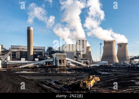 Ein schweres Kraftwerk, das Kohle aus einem fossilen Brennstoffstapel in einem großen Kohlekraftwerk abkratzt, um nicht erneuerbare Energie zu erzeugen Stockfoto