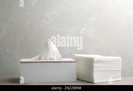 Schachtel mit Taschentüchern und einem Stapel Servietten auf dem Tisch Stockfoto
