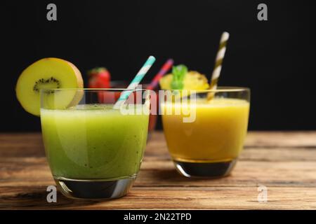 Köstliche bunte Säfte in Gläsern auf Holztisch, Nahaufnahme Stockfoto