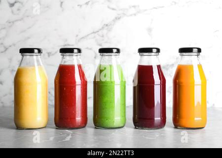 Flaschen mit köstlichen bunten Säften auf dem Marmortisch Stockfoto