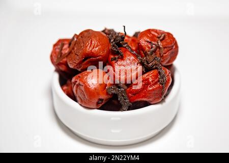 Japanische Umeboshi, traditionelle Art fermentierter, gesalzener Pflaume mit roten Shiso-Blättern. Nahaufnahme Stockfoto