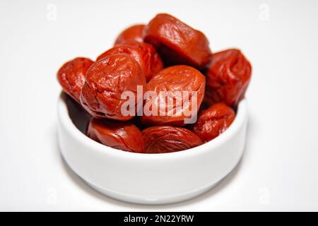 Japanische Umeboshi, traditionelle Art fermentierter, gesalzener Pflaume mit roten Shiso-Blättern. Nahaufnahme Stockfoto