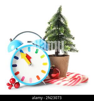 Wecker mit kleiner Tanne, festlicher Einrichtung und Zuckerstangen auf weißem Hintergrund. Der Countdown für das neue Jahr Stockfoto