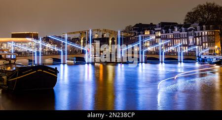 AMSTERDAM, NIEDERLANDE - 18. JANUAR 2023: Amsterdam Light Festival - Brücke 242 (Magere Brücke) an der Amstel. Panoramablick. Stockfoto