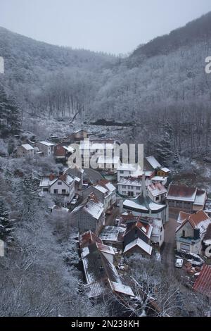 Falkenstein, Deutschland - 31. Januar 2021: Häuser in einem Tal, umgeben von Hügeln mit schneebedeckten Bäumen an einem kalten Wintertag in Rheinland-Pfalz Stockfoto
