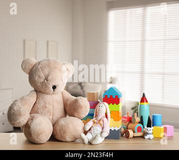 Set mit verschiedenen niedlichen Spielzeugen auf Holztisch im Kinderzimmer Stockfoto